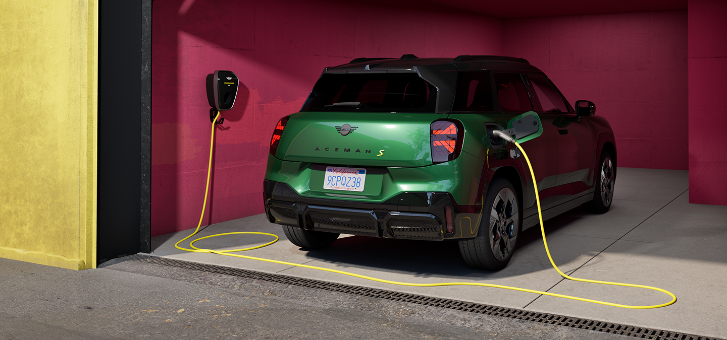 Vue arrière de la MINI Aceman Electric British Racing Green en charge dans un garage. 