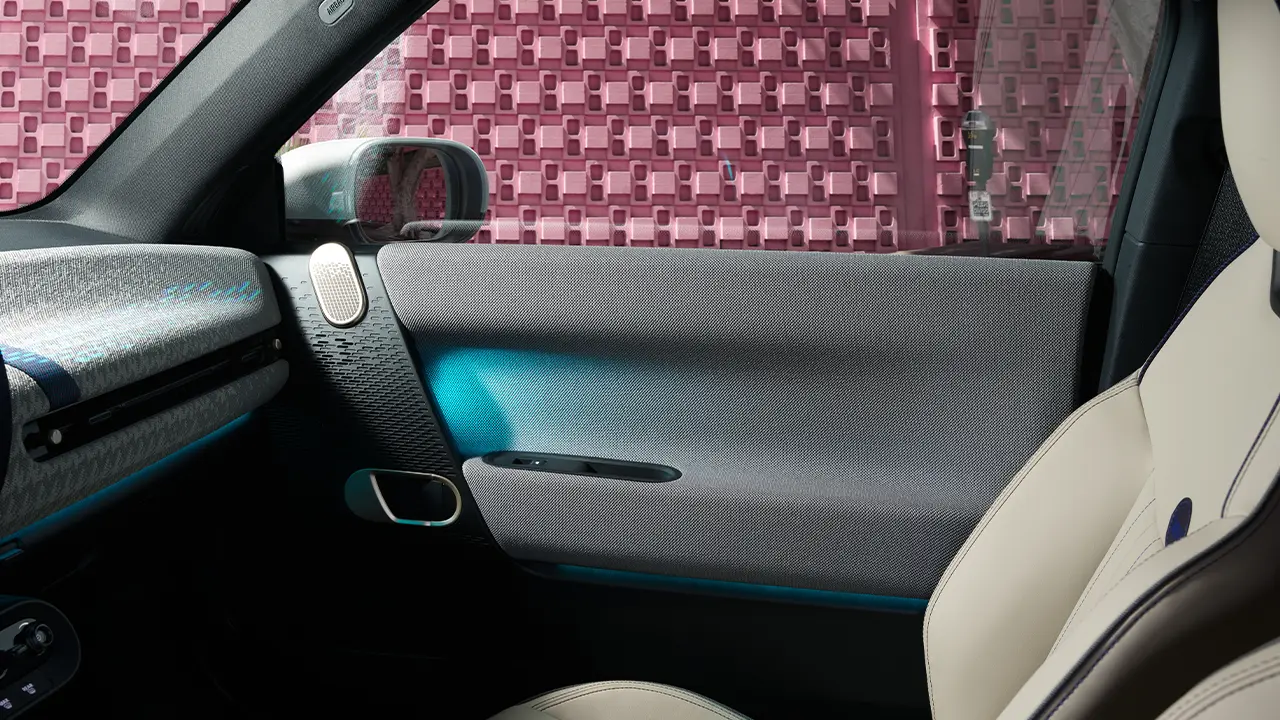 Vue intérieure d’une portière de MINI Cooper Electric avec éclairage d’ambiance bleu