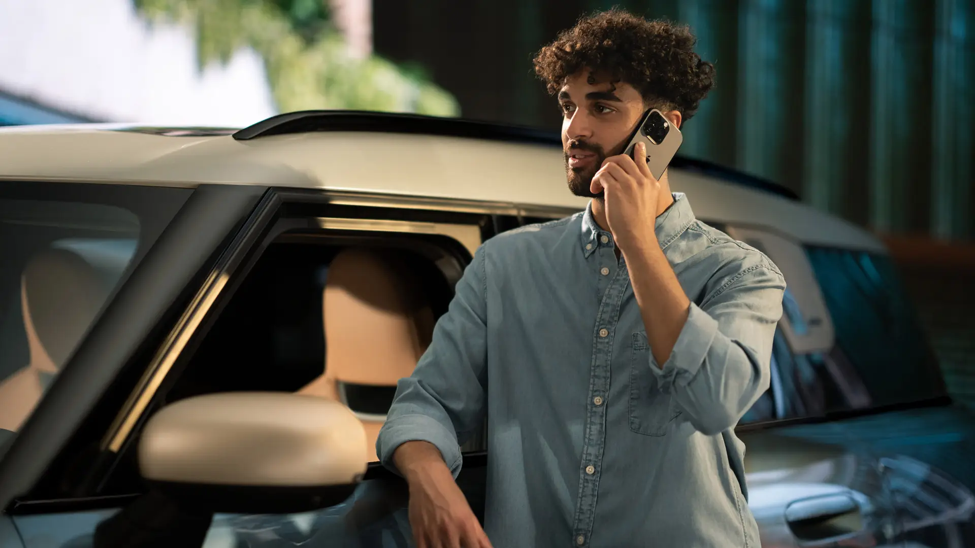 MINI Proactive Care : un homme se tient à côté de sa MINI et discute au téléphone avec un consultant du centre de service.