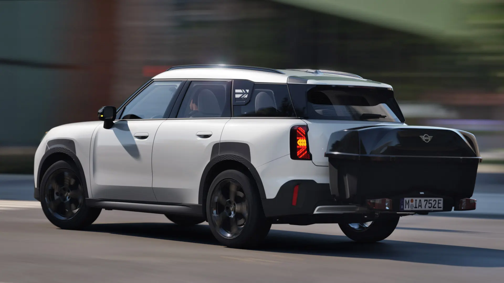 Vue latérale arrière du MINI Aceman en Nanuq White équipé d'un porte-vélos arrière MINI avec compartiment arrière MINI. 