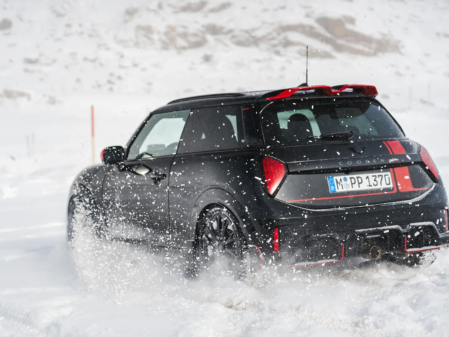 Vue arrière d'une MINI Cooper JCW pendant la conduite dans la neige.
