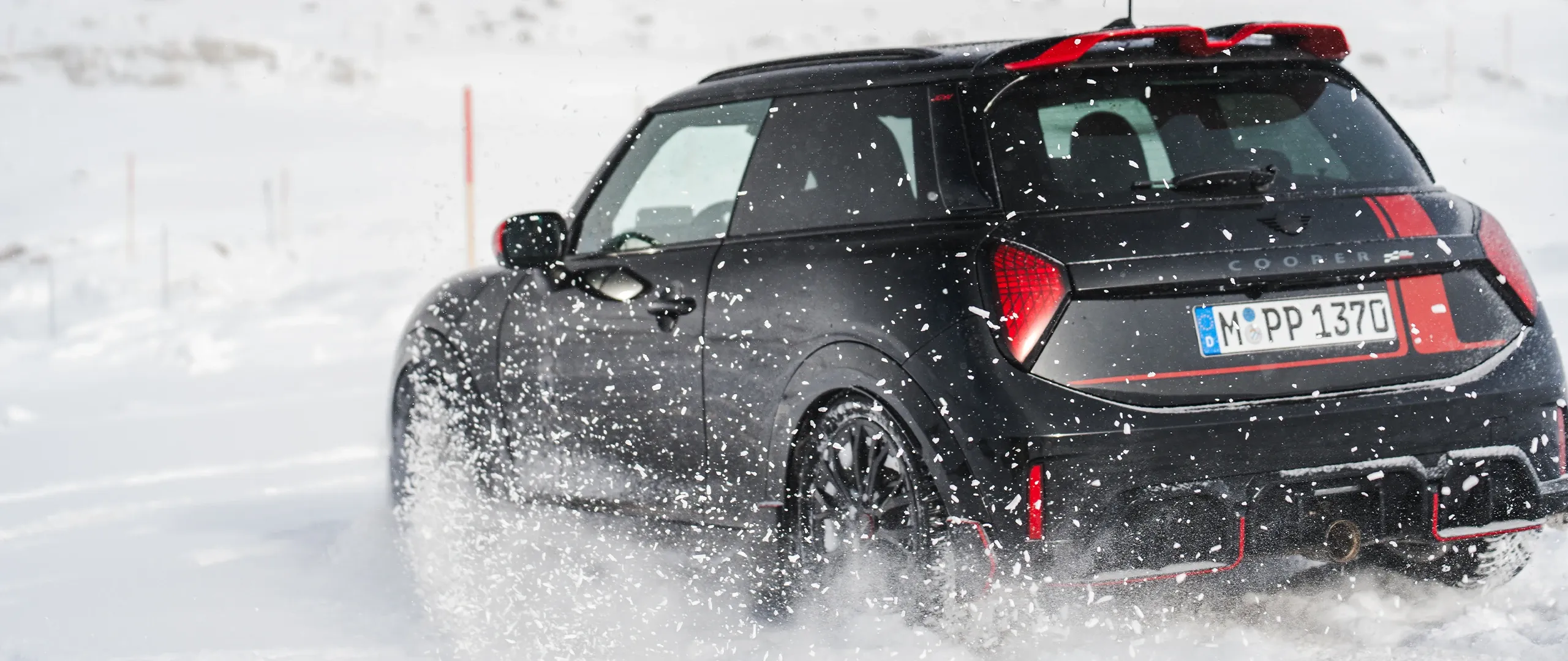 Vue arrière d'une MINI Cooper JCW pendant la conduite dans la neige.