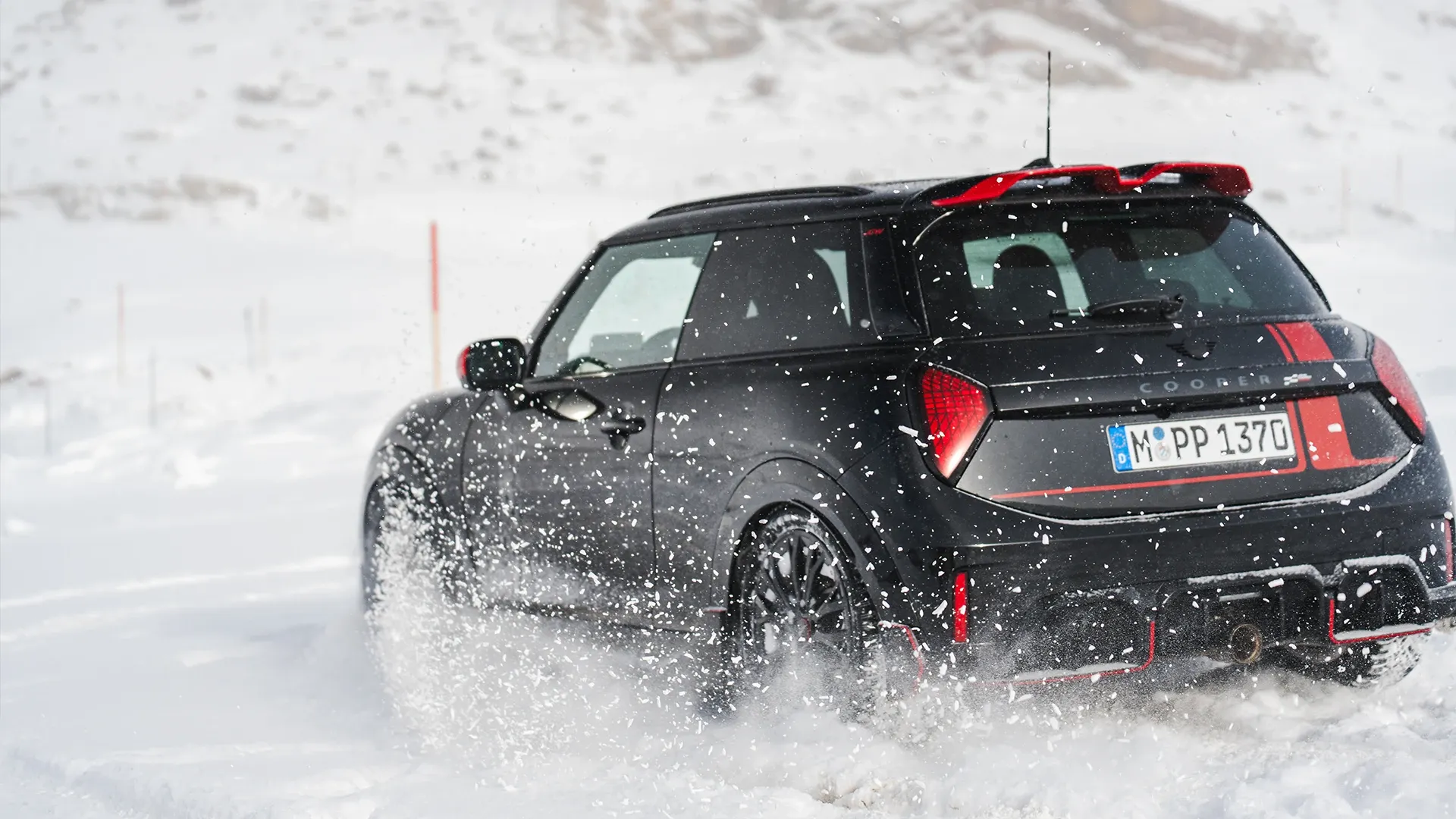 Vue arrière d'une MINI Cooper JCW pendant la conduite dans la neige.