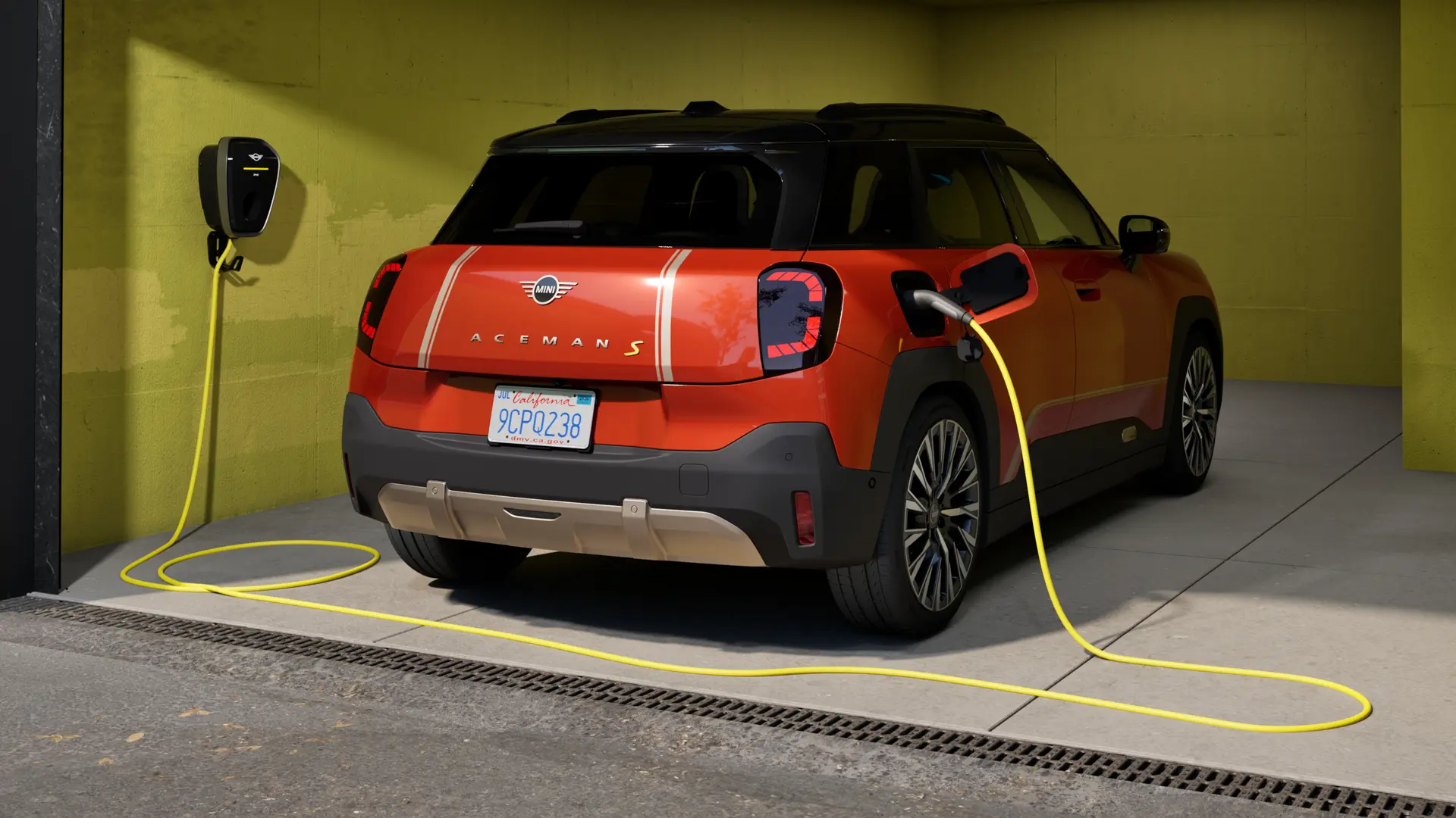 MINI Aceman S 100 % électrique stationné dans un garage, en cours de recharge avec la MINI Wallbox Plus, vue arrière.