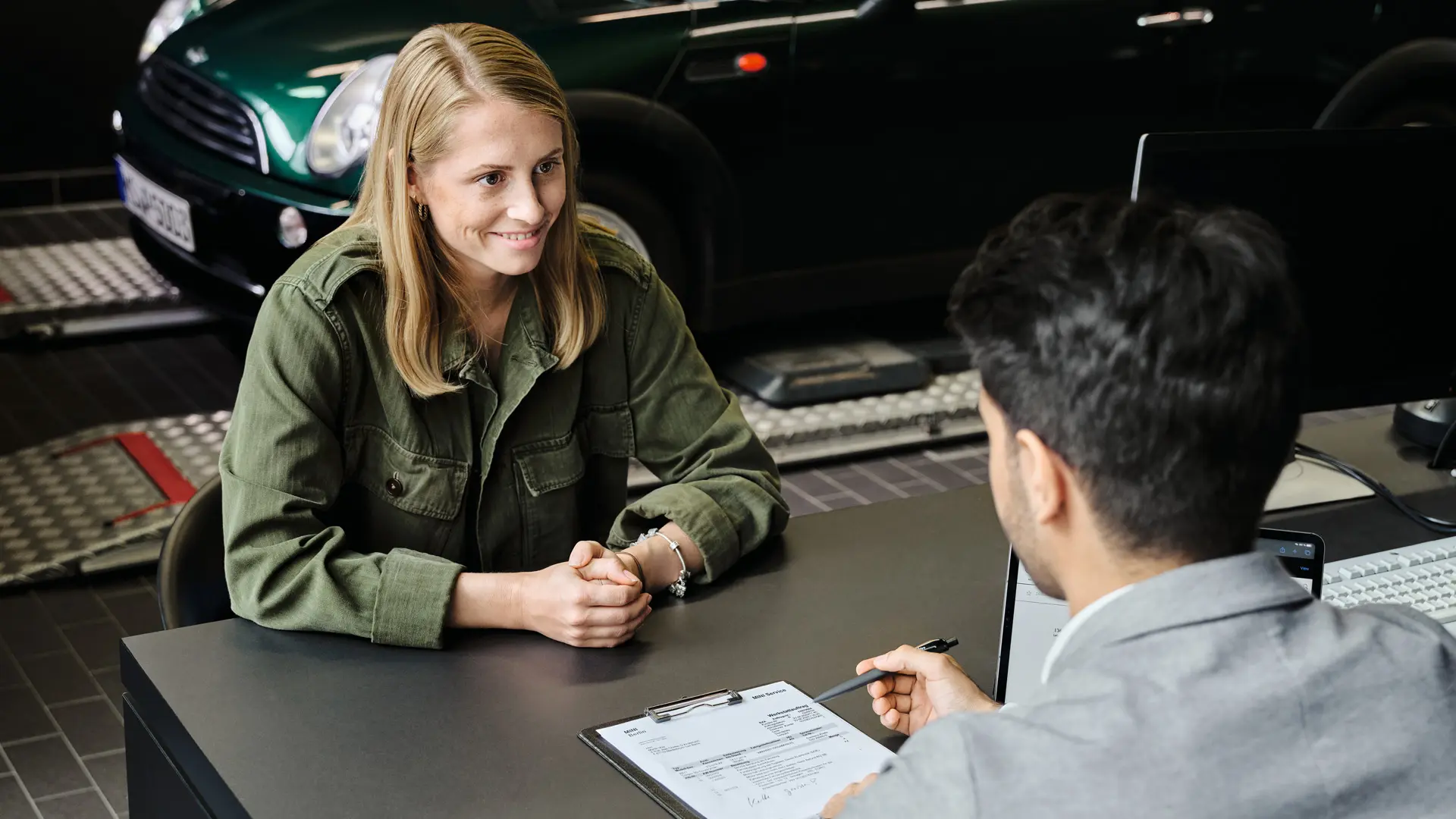 Concession MINI avec une conseillère qui explique à une cliente les options de service, toutes les deux assises à une table.