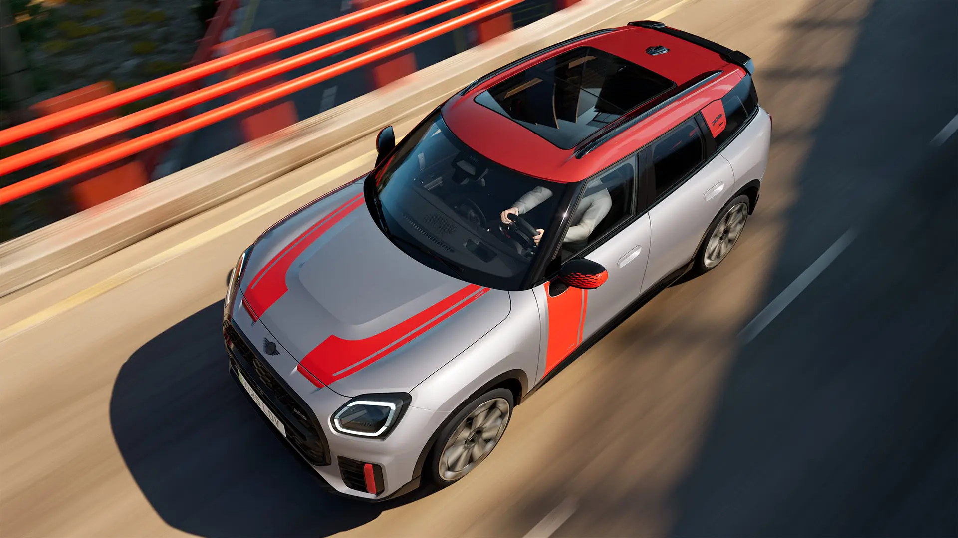MINI Countryman John Cooper Works en Melting Silver avec coquille de rétroviseur, films latéraux et de capot, toit et ailettes Chili Red, roulant en ville, vue de face.