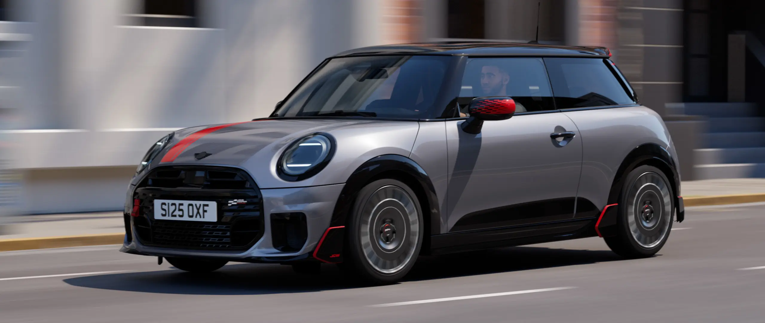 MINI Cooper 3 portes en Melting Silver avec coquille de rétroviseur John Cooper Works et film de capot Chili Red, becquet de toit et ailettes Black, roulant en ville, vue de face.