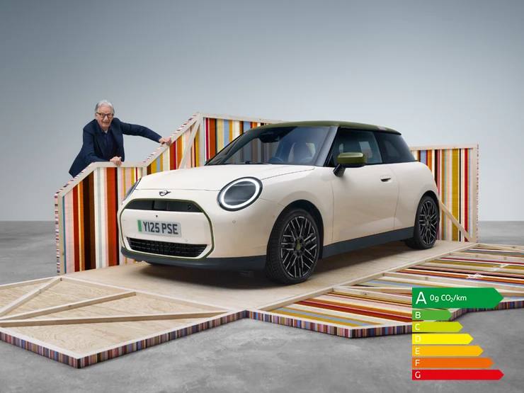 Vue latérale avant de la MINI Cooper Paul Smith Edition 100 % électrique en Inspired White avec le designer Paul Smith