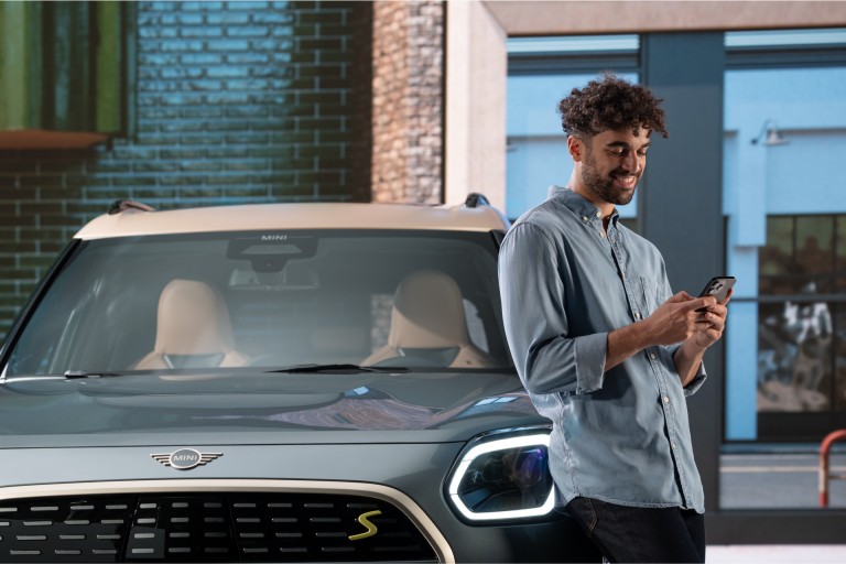 MINI vue de face, détail, avec un homme s'appuyant sur la MINI